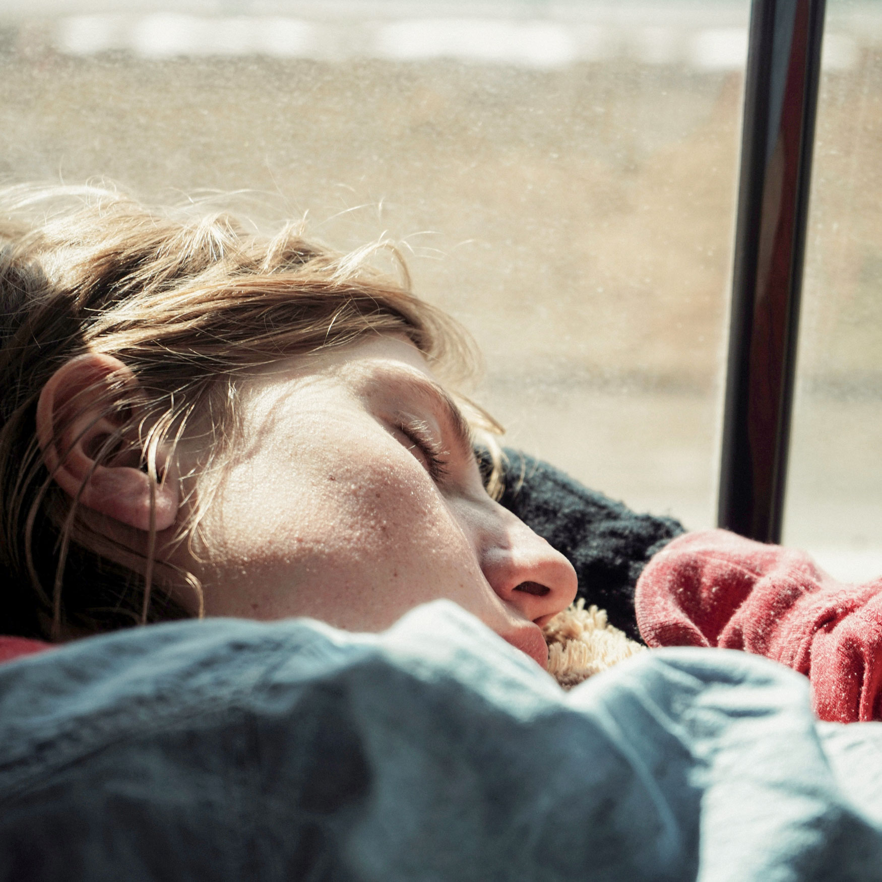 Erschöpfte Frau lehnt sich an Fenster.